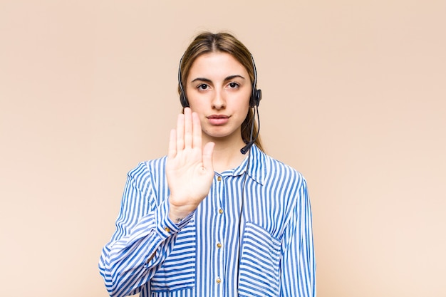 Photo blonde pretty woman looking serious, stern, displeased and angry showing open palm making stop gesture