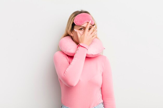 Blonde pretty woman looking shocked scared or terrified covering face with hand