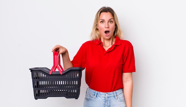 Blonde pretty woman looking very shocked or surprised shopping basket concept