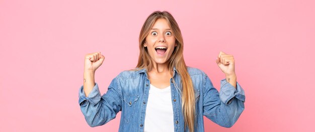 Blonde pretty woman shouting aggressively with an angry expression or with fists clenched celebrating success