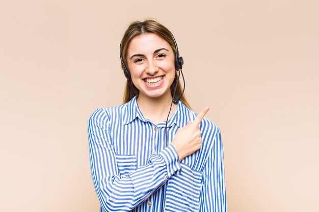 Blonde pretty woman smiling cheerfully, feeling happy and pointing to the side