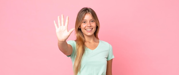 Blonde pretty woman smiling and looking friendly, showing number five or fifth with hand forward, counting down