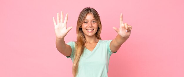 Foto bella donna bionda che sorride e sembra amichevole, mostra il numero sette o settimo con la mano in avanti, conto alla rovescia