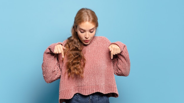 両手で下向きに口を開けた金髪のきれいな女性