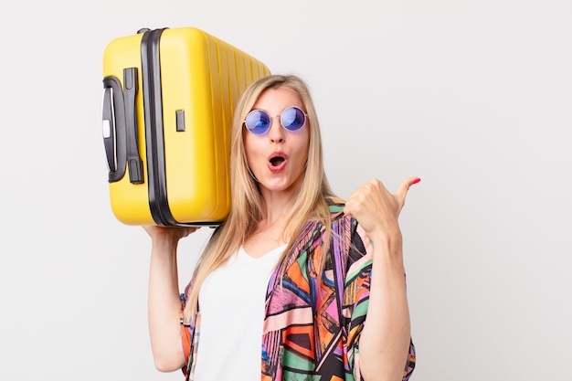 スーツケースを持つ金髪のきれいな女性。夏のコンセプト
