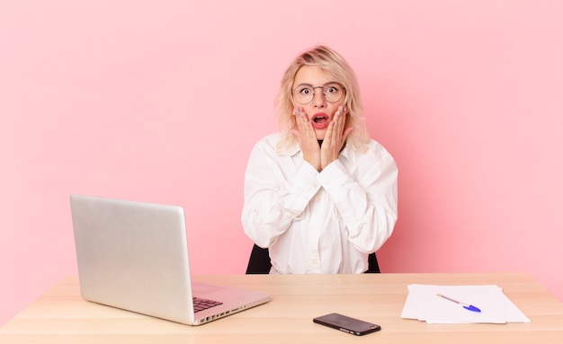 Blonde pretty woman young pretty woman feeling shocked and scared. workspace desk concept