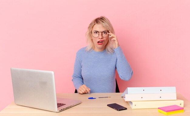 Blonde pretty woman young pretty woman looking surprised, realizing a new thought, idea or concept. workspace desk concept