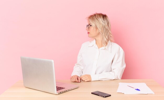 Blonde pretty woman young pretty woman on profile view thinking, imagining or daydreaming. workspace desk concept