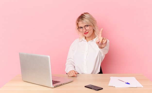 Blonde pretty woman young pretty woman smiling proudly and confidently making number one. workspace desk concept