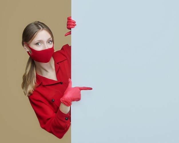 Блондинка в красных перчатках и маске позирует с большим пустым рекламным щитом.