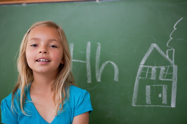 Blonde schoolmeisje poseren voor een schoolbord