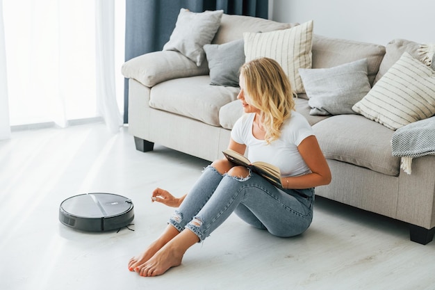 Photo blonde sits on the floor woman in casual clothes is indoors at home