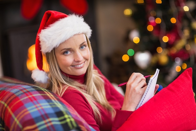 Blonde sitting on the couch writing her christmas list