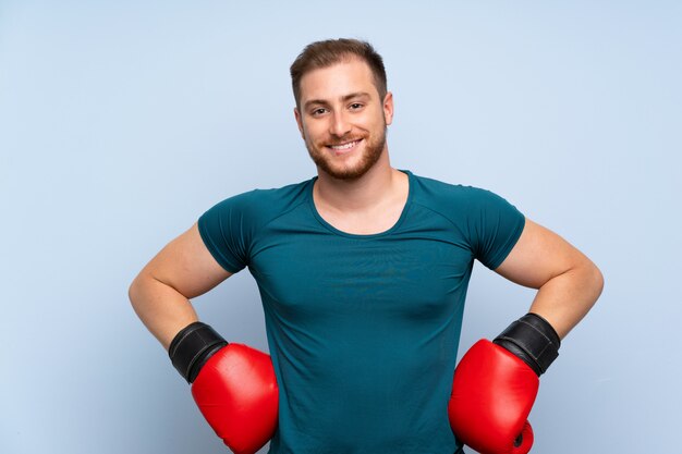 Blonde sport man over blauwe muur met bokshandschoenen