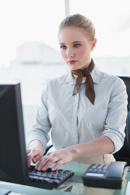 Blonde strenge onderneemster die aan computer werken