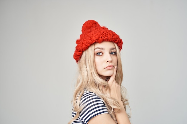 Blonde in a striped Tshirt Red Hat light background Lifestyle High quality photo