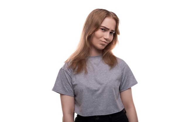 Photo blonde teenage girl of european appearance with braces in a gray tshirt on a background with copy