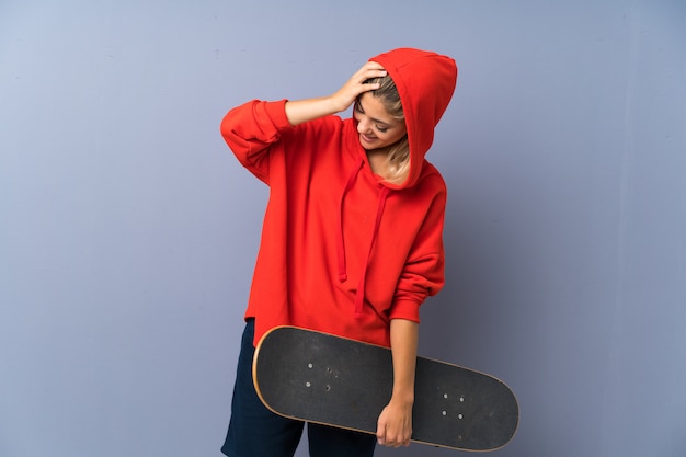 Photo blonde teenager skater girl over grey wall