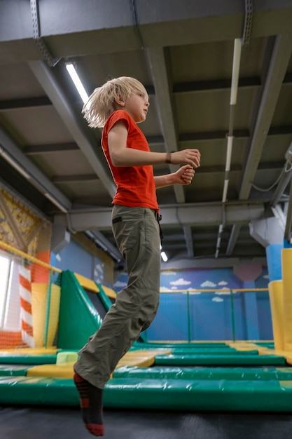 Blonde tiener springt op trampoline in een uitgaanscentrum voor kinderen Verticaal frame