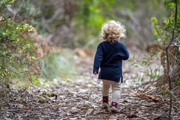 blonde todder walking in a forest on a hike