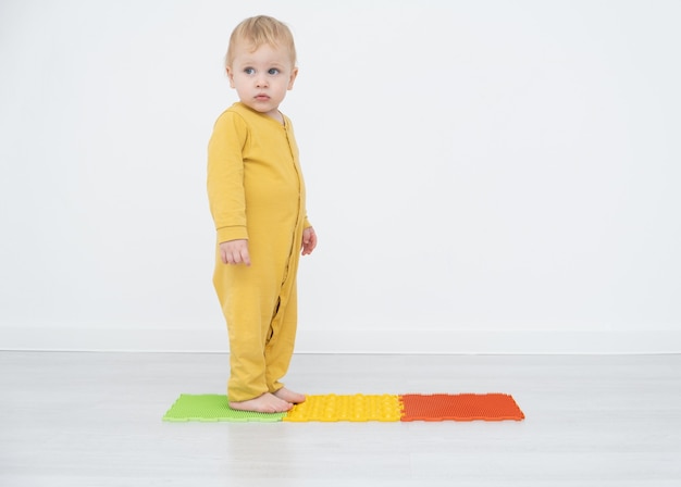 Blonde toddler standing on an orthopedic Mat