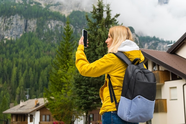 Blonde toerist maakt foto's met smartphone van mistige Alpenbergen