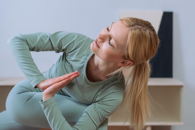 Blonde in a tracksuit practicing yoga at home