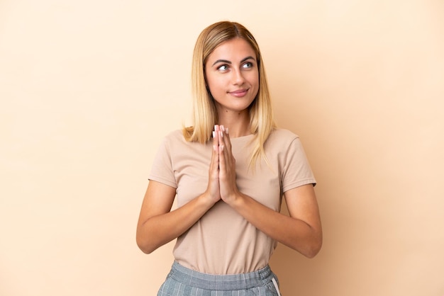 Blonde Uruguayan girl isolated on beige background scheming something