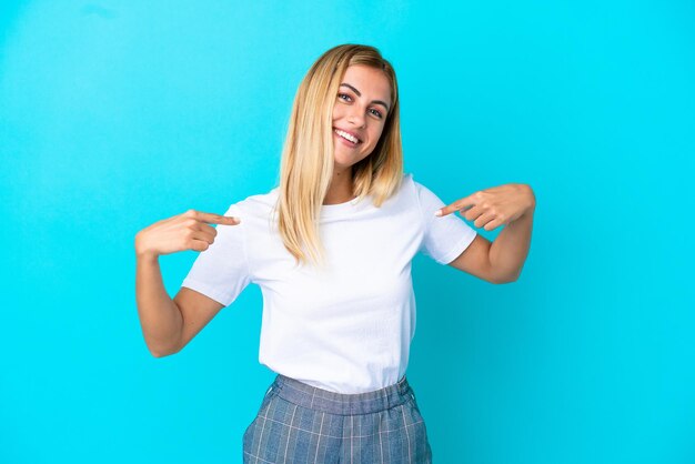 Blonde Uruguayan girl isolated on blue background proud and selfsatisfied