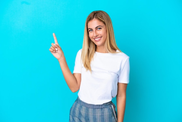 Blonde Uruguayan girl isolated on blue background showing and lifting a finger in sign of the best