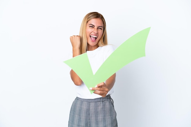 Blonde Uruguayan girl isolated on white background holding a check icon and celebrating a victory