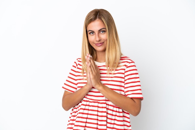 Blonde Uruguayan girl isolated on white background keeps palm together Person asks for something