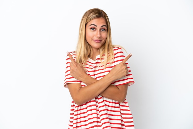 Blonde Uruguayan girl isolated on white background pointing to the laterals having doubts