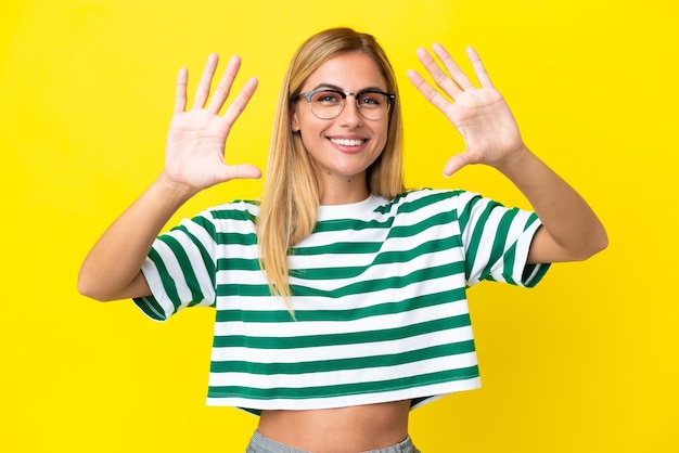 Blonde Uruguayan girl isolated on yellow background counting ten with fingers