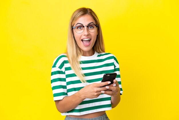 Blonde uruguayan girl isolated on yellow background surprised and sending a message