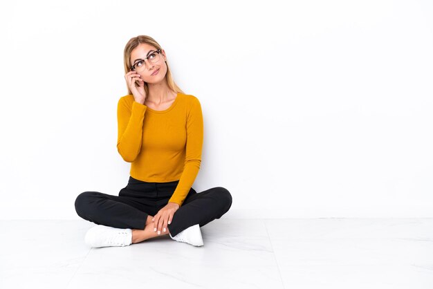 Blonde Uruguayan girl sitting on the floor thinking an idea