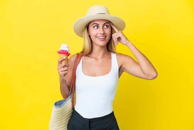 Блондинка из Уругвая летом держит мороженое на желтом фоне, сомневается и думает