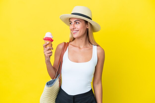 여름에 금발 우루과이 소녀 노란색 배경 찾고 측면에 고립 된 아이스크림을 들고