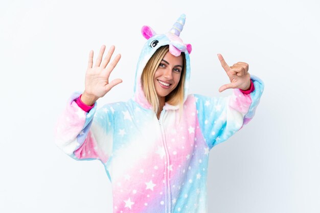 Blonde Uruguayan girl wearing a unicorn pajama isolated on white background counting seven with fingers