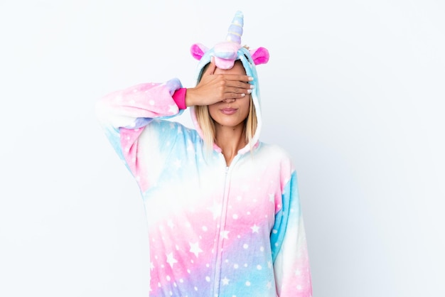 Blonde Uruguayan girl wearing a unicorn pajama isolated on white background covering eyes by hands Do not want to see something