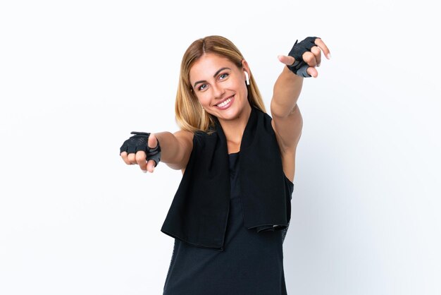 Blonde Uruguayan sport girl isolated on white background points finger at you while smiling