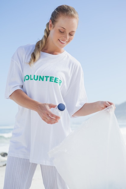 Blonde volunteer picking up trash on the beach