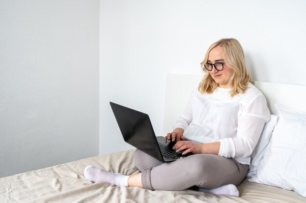 Blonde vrouw die aan laptop thuis werkt