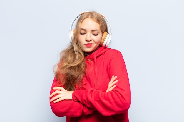 Blonde vrouw die haar schouders ophaalt, zich verward en onzeker voelt, twijfelt met gekruiste armen en verbaasde blik