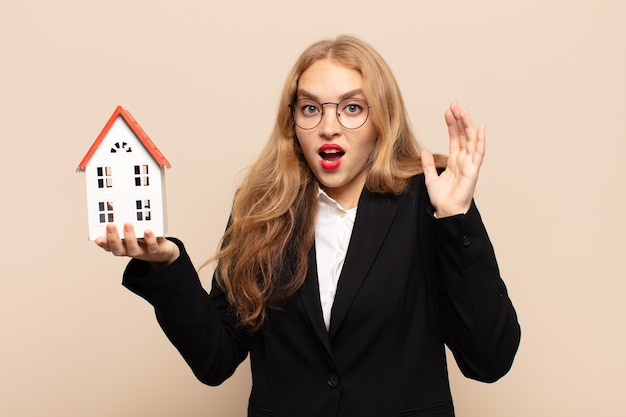 Blonde vrouw die met handen in de lucht schreeuwt, zich woedend, gefrustreerd, gestrest en boos voelt