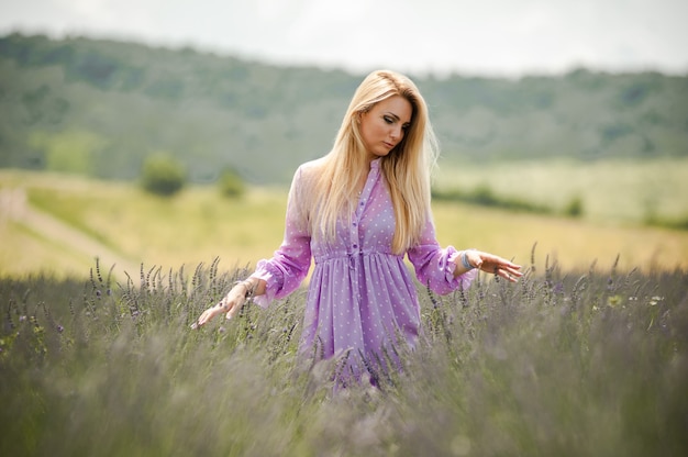 Blonde vrouw die op het lavendelveld loopt