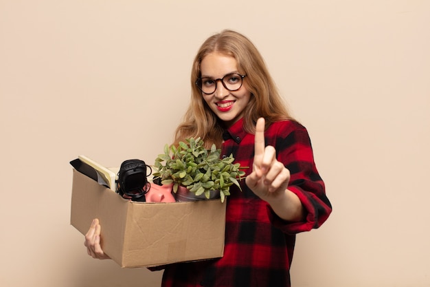 Blonde vrouw die trots en zelfverzekerd glimlacht en nummer één triomfantelijk laat poseren, zich een leider voelt