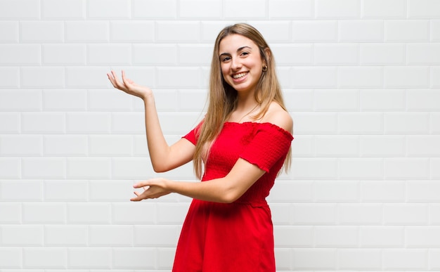 Blonde vrouw die trots en zelfverzekerd glimlacht, zich gelukkig en tevreden voelt en een concept op exemplaarruimte toont