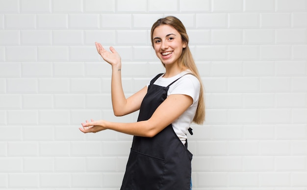 Blonde vrouw die trots en zelfverzekerd glimlacht, zich gelukkig en tevreden voelt en een concept op exemplaarruimte toont