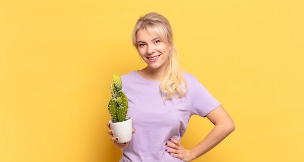 Blonde vrouw die vrolijk lacht met een hand op de heup en zelfverzekerd